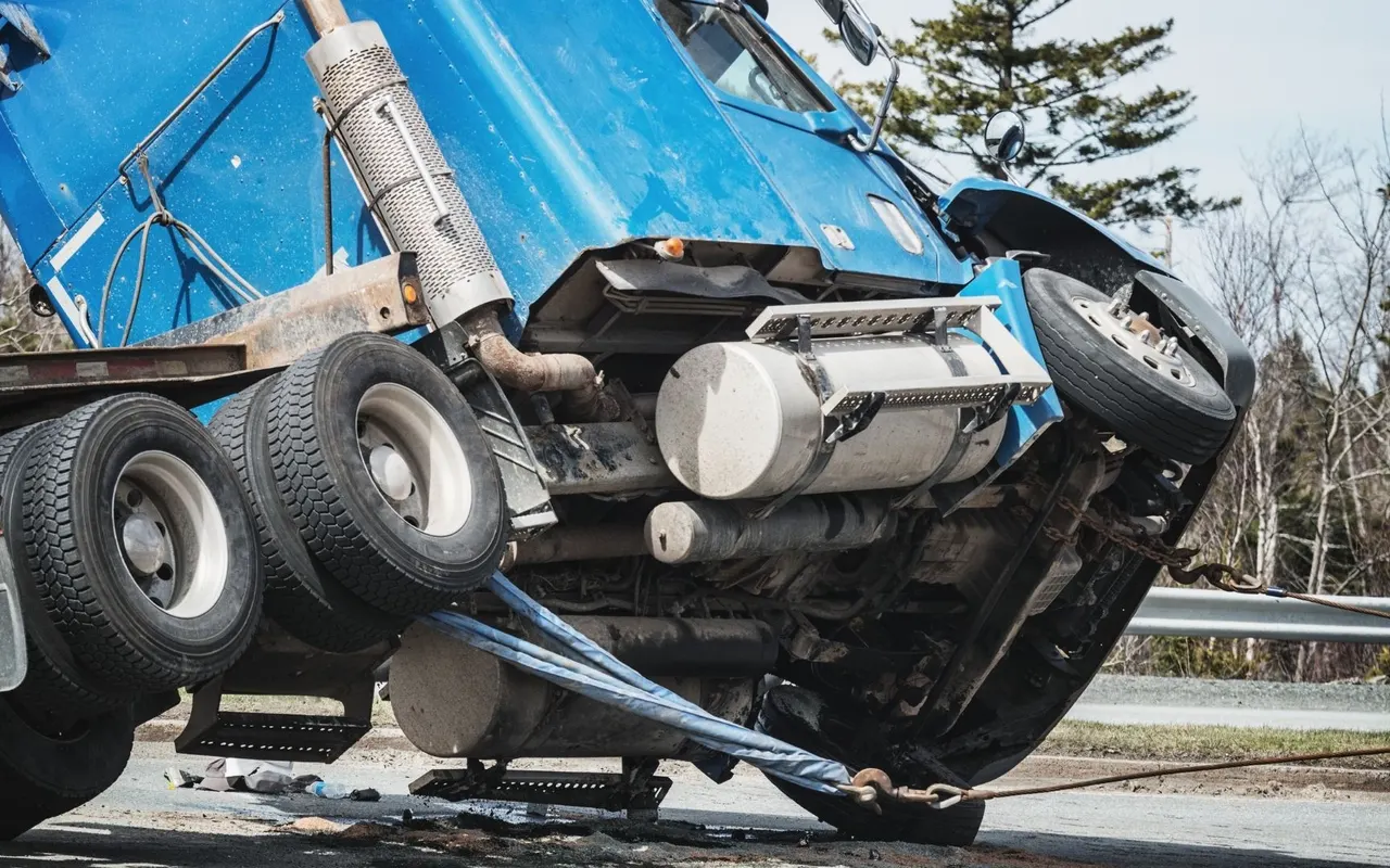 Heavy truck being recovered at the roadside with straps