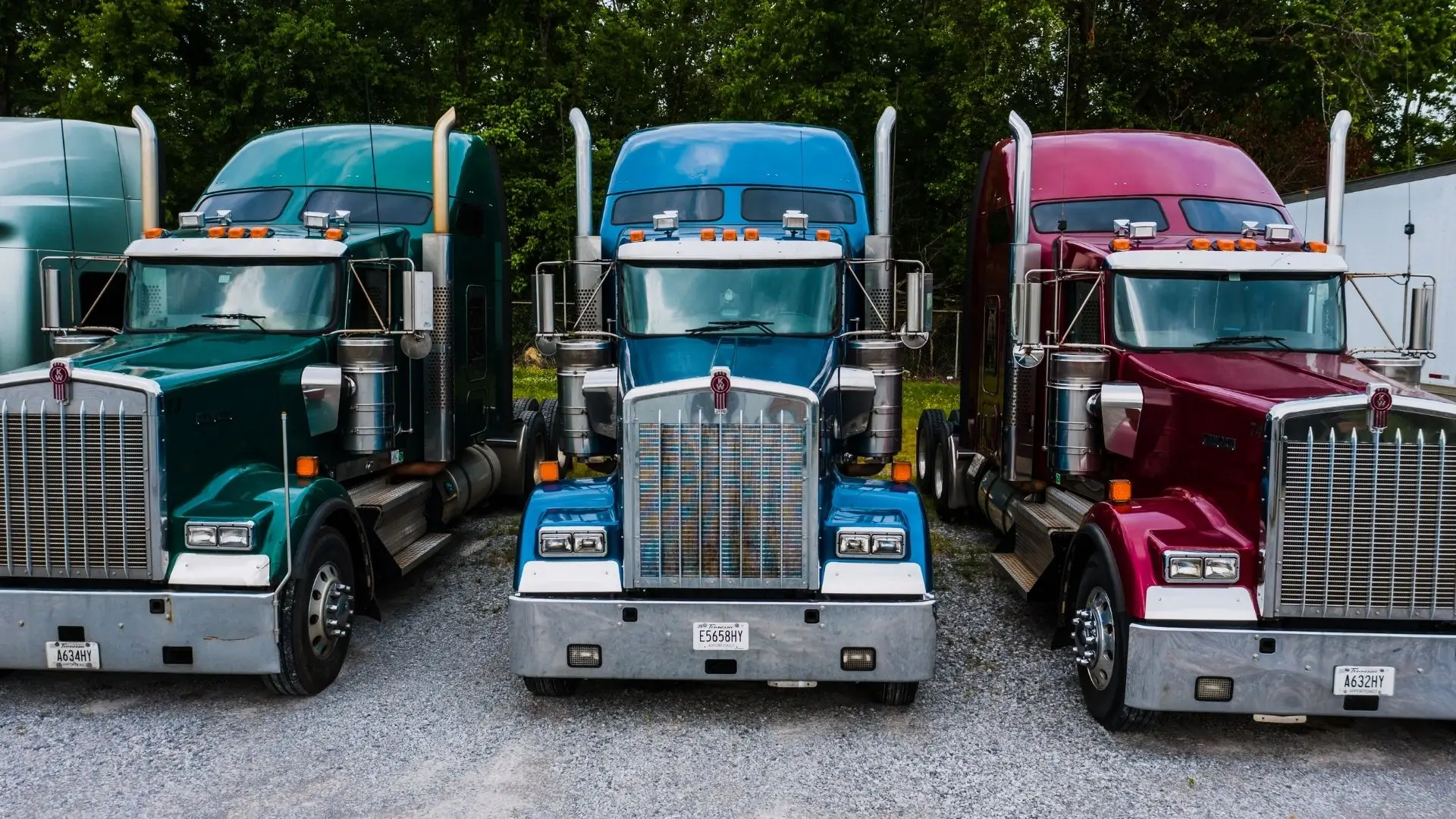 Three heavy trucks parked side by side at a depot