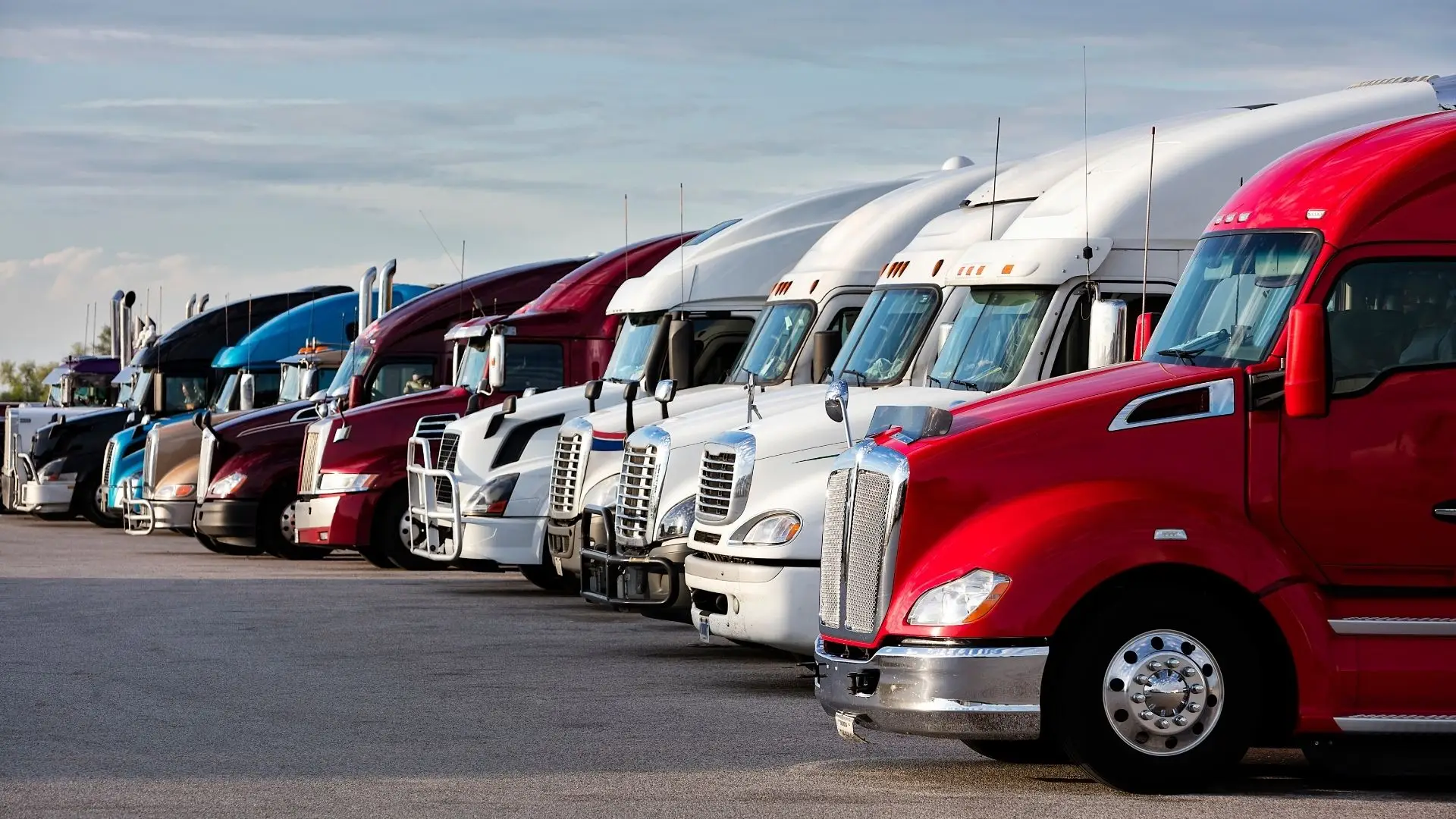 Line of parked commercial trucks at a highway yard