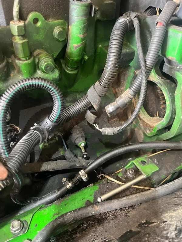 John Deere engine wiring and hose repair in progress