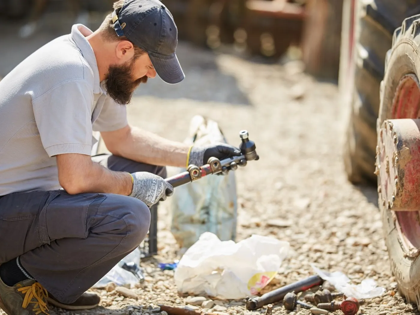 Mechanic repairing a tractor steering component out in a field