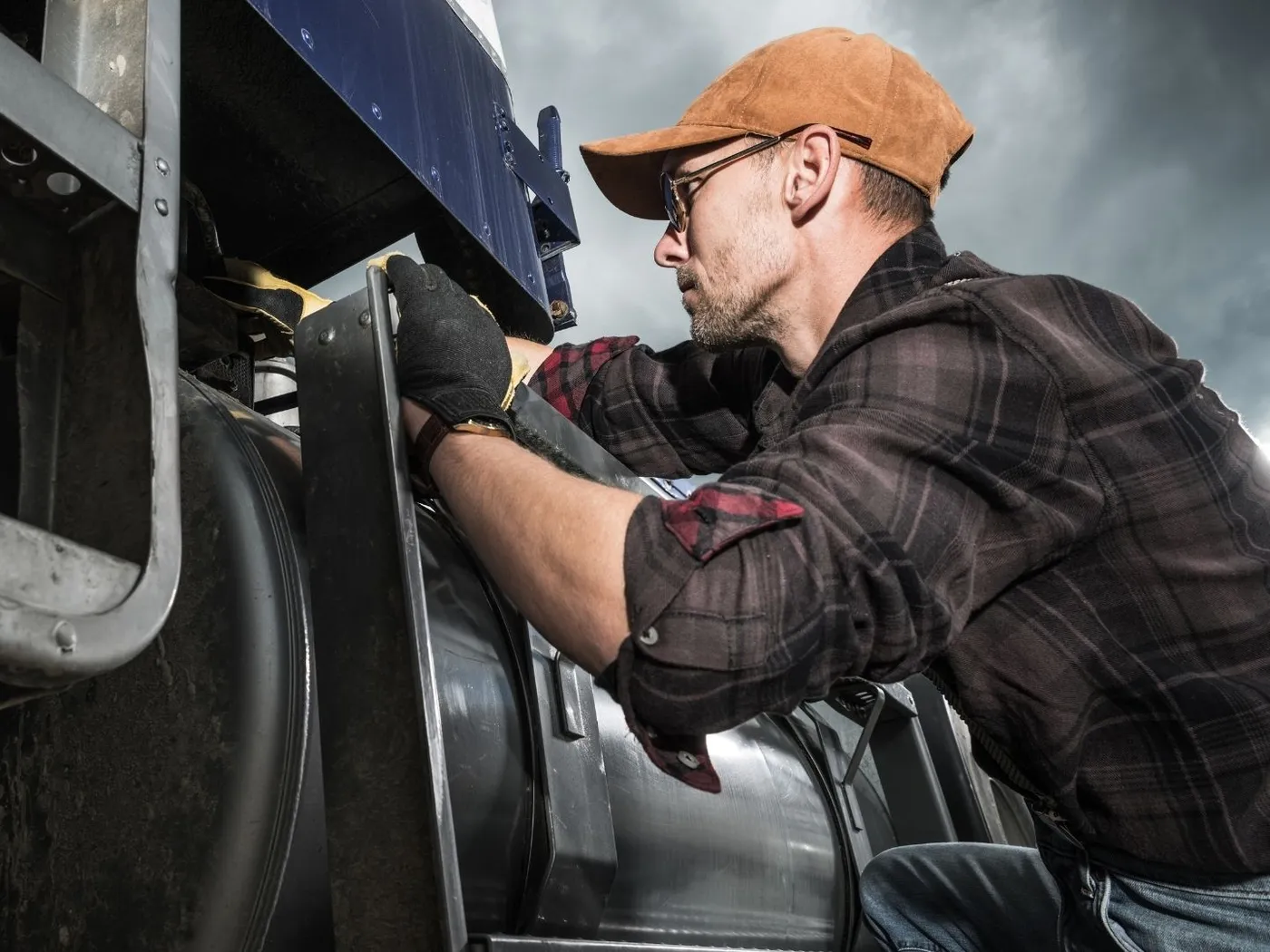 Mechanic working on a truck at the roadside under a dark sky