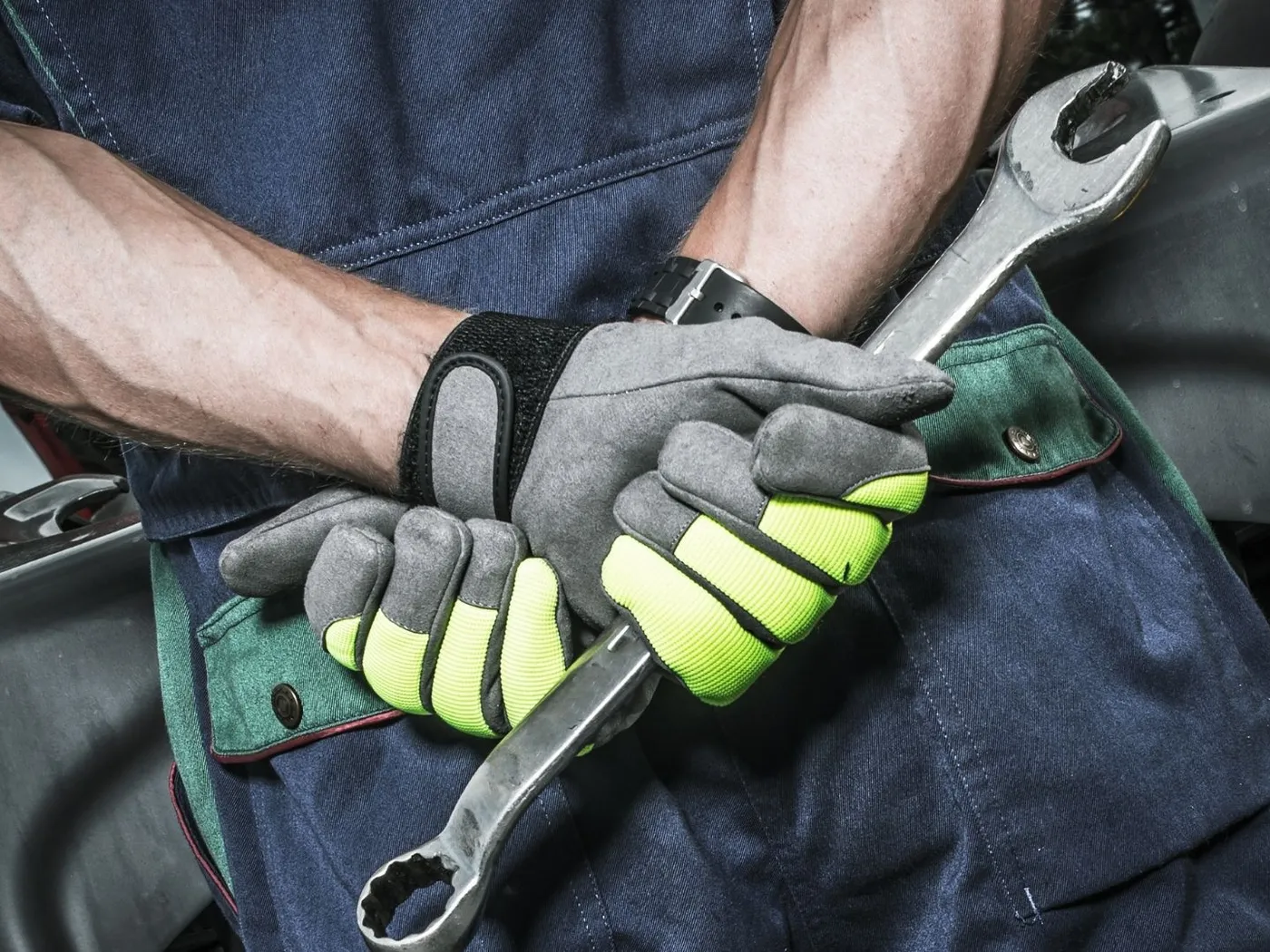 Close view of a mechanic's gloved hands holding wrenches